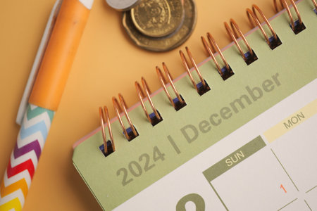 The December 2024 Calendar features a Pen and Coins on a vibrant Yellow Backgroundの写真素材