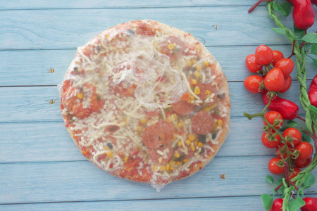 Delicious Frozen Pizza Featuring Cheese and Various Toppings, All Wrapped Securely in Plasticの写真素材