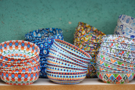A beautiful array of colorful handpainted ceramic bowls elegantly displayed for saleの写真素材