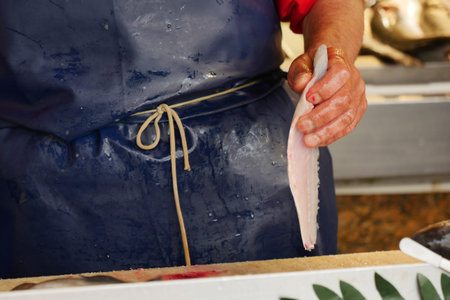 A skilled chef carefully prepares a fresh fish fillet at the local market, showcasing his craft