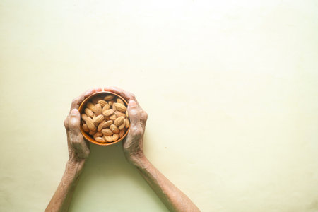 close up senior women hand holding a bowl on almondの写真素材
