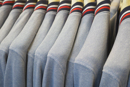 A collection of stacked gray Tshirts featuring vibrant and colorful stripes displayed on hangersの写真素材