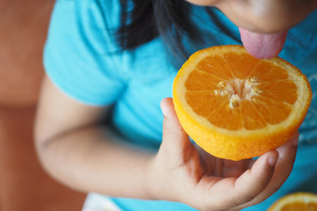 A Child Enjoys an Orange Slice with Delightful Anticipation and Joyful Excitement in the Moment