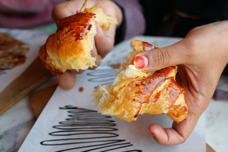 A Freshly Baked Croissant Deliciously Being Shared Among Friends and Family Membersの写真素材