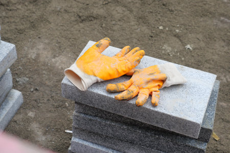 Durable Construction Gloves Placed on Stacked Tiles at a Busy Worksite Amid Ongoing Projectsの写真素材