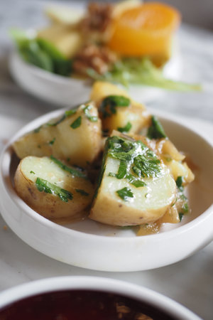 Delicious Herbed Boiled Potatoes Served Alongside Fresh Greens for a Wholesome Mealの写真素材