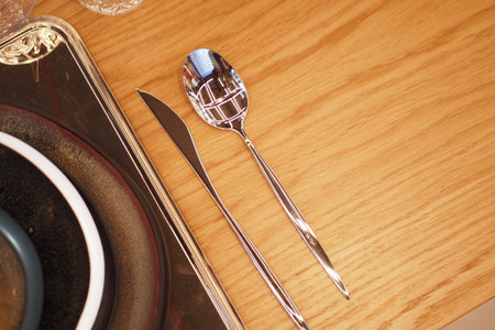 An Elegant Table Setting with a Spoon and Knife placed beautifully on a Wooden Tableの写真素材