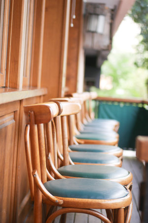 Beautiful and Elegant Wooden Bar Stools Featuring Green Cushions on a Cozy Balcony Settingの写真素材