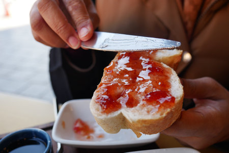 Spreading Jam on Fresh Toast at a Cafの写真素材