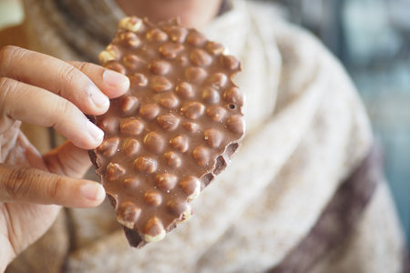 A closeup view of a hand holding a delicious chocolate wafer snack, full of allureの写真素材