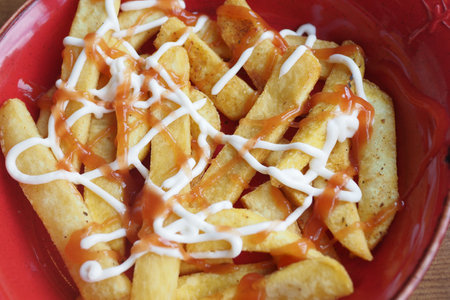 Scrumptious Golden Fries Drizzled with Rich Ketchup and Creamy Mayonnaise on Topの写真素材