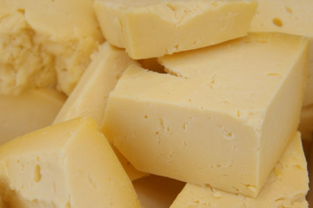 Indulge in the delightful experience of Freshly Cut Yellow Cheese Blocks, bursting with flavorの写真素材