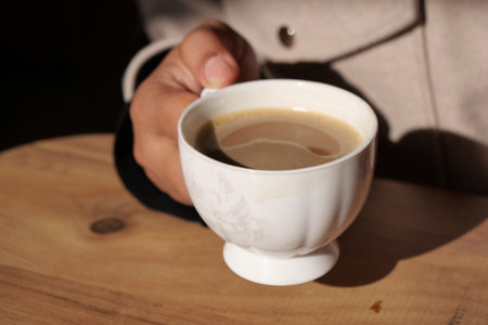 Enjoying a cozy moment while holding a steaming cup of warm coffee on a pleasant afternoon