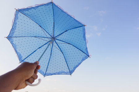 A Bright Blue Polka Dot Umbrella Set Against a Beautifully Clear and Clear Sky Above, Glowingの写真素材