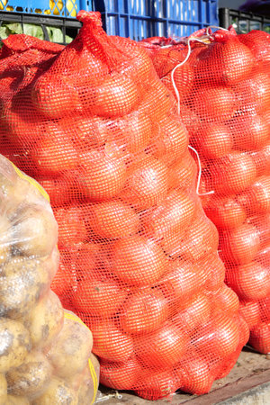 Brightly Colored Sacks Filled with Freshly Harvested Onions and Potatoes at the Marketの写真素材