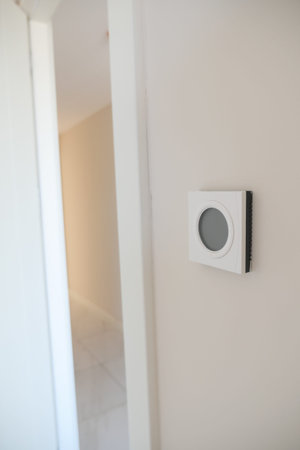 Smart Thermostat on White Wall for Optimal Home Temperature Controlの写真素材
