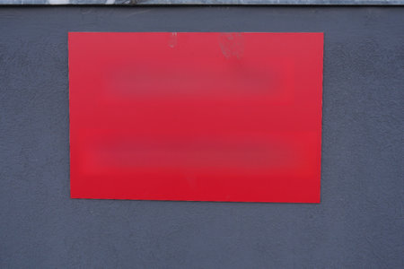 A bold and solid red sign is prominently displayed on a stylish gray wall backgroundの写真素材