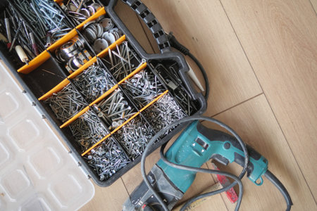 A wood flooring with a toolbox containing screws and drills