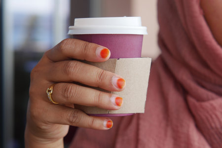 Individual Grasping a Coffee Cup with Beautiful and Colorful Nail Art on Displayの写真素材