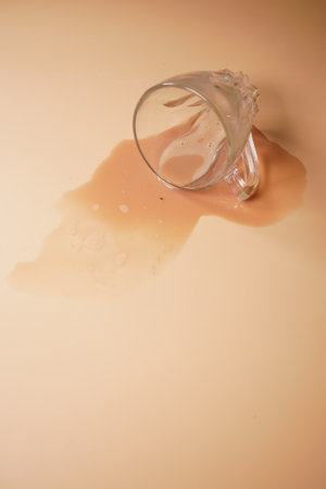 A Spilled Glass of Water Accidentally Poured on a Beige Surface, Creating an Interesting Sceneの写真素材