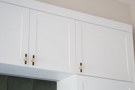 Discover the beauty of Elegant White Kitchen Cabinets adorned with exquisite Gold Accentsの写真素材