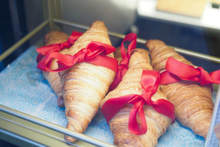 Beautiful and Elegant Croissants Beautifully Tied with Bright Red Ribbons in a Display Caseの写真素材
