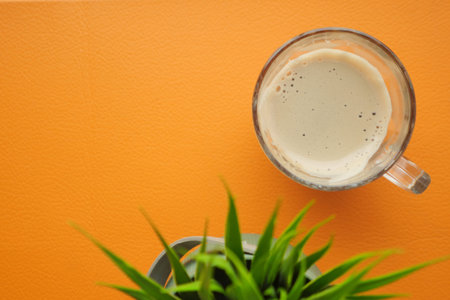 A Beautiful Aerial View Showcasing a Coffee Mug and a Succulent Plant on an Orange Background