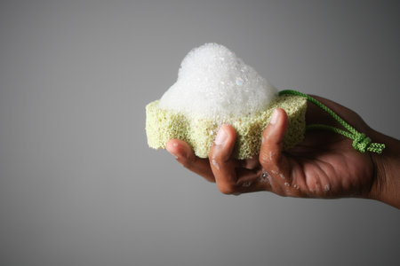 A Hand Gently Holding a Soapy Bath Sponge Covered with Luxurious Foam and Bubblesの写真素材