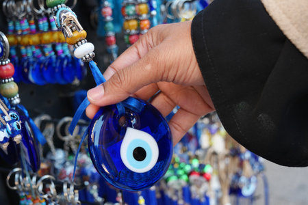 A Hand Selecting an Intriguing Blue Eye Amulet from a Delightfully Colorful Displayの写真素材
