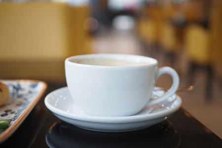 An Elegant White Coffee Cup Placed on a Saucer in a Contemporary Cafe Setting with Styleの写真素材