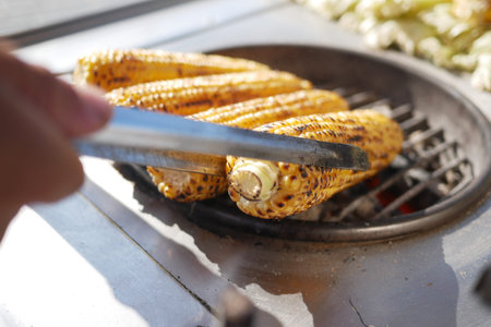Grilling a delicious ear of corn on the cob during a sunny and warm summer day outdoors