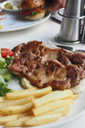 grill chicken meat served with chips and fresh salad on a plateの写真素材