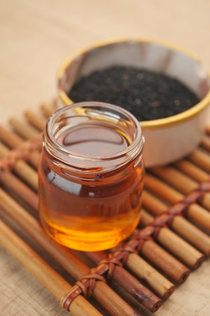 Black Seeds and Their Oil Beautifully Arranged in a Rustic Wooden Bowl for Culinary Usesの写真素材