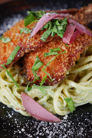 Enjoy the delightful combination of Crispy Chicken served over Creamy Pasta with Fresh Herbsの写真素材