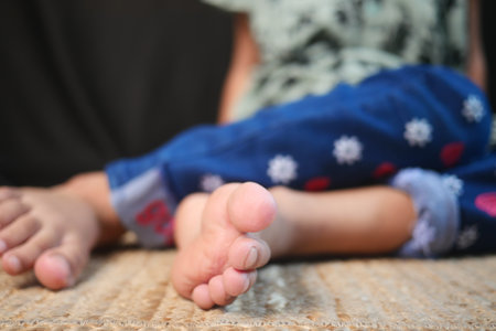 The Playful and Carefree Child is Sitting on a Soft Rug, Showcasing Their Joyful Feetの写真素材