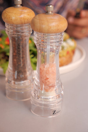 Essential Seasonings Salt and Pepper Grinders Beautifully Placed on a Dining Table Settingの写真素材