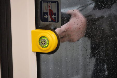 finger presses button to open doors in subway car.