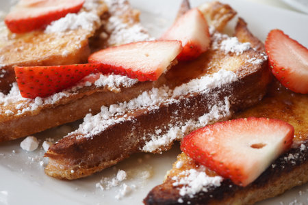Indulge in delicious French toast topped with fresh strawberries and sprinkled with powdered sugarの写真素材
