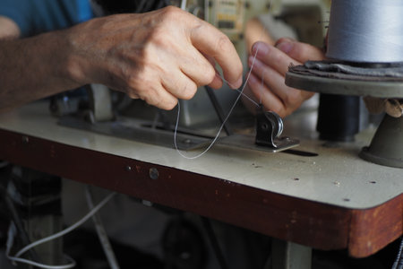 A closeup view of hands skillfully using a sewing machine for tailoringの写真素材
