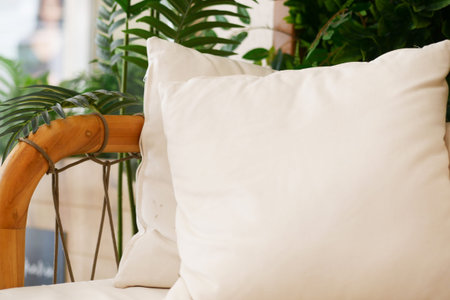 Cozy Neutral Pillow on Rattan Chair Surrounded by Lush Foliageの写真素材