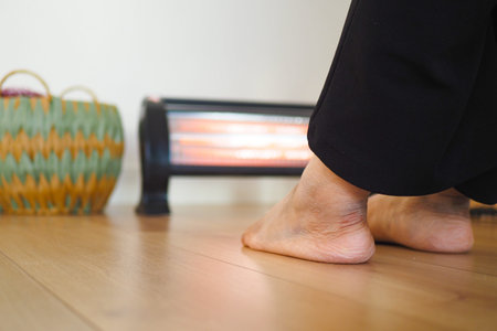 Cozy Home Scene With Feet Warming Near Electric Heaterの写真素材