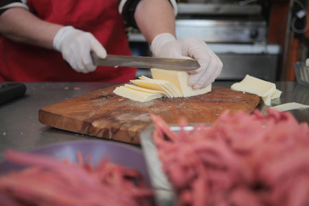 A chef skillfully slices butter and meat in an organized kitchenの写真素材