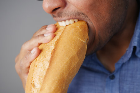A Man Savoring a Fresh and Delicious Baguette Bite with Pleasureの写真素材