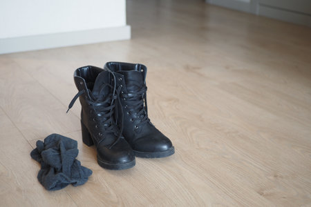A stylish pair of black laceup boots and cozy socks on a wooden floorの写真素材