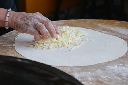Cheese Being Added to Dough for the Preparation of a Delicious Dishの写真素材
