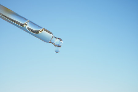 Close-up of a Droplet from a Pipette Against a Clear Blue Skyの写真素材