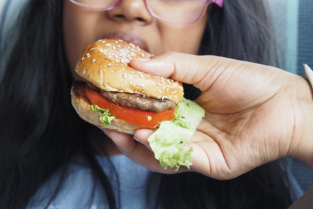 A Hand Holding a Delicious Burger for a Childs Meal Experienceの写真素材