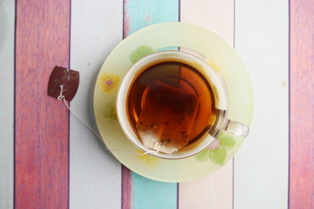 A Cup of Aromatic Tea Resting on a Colorful Wooden Table Surfaceの写真素材