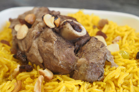 Enjoy a Savory Lamb Shank Served on Aromatic Yellow Rice Topped with Nutsの写真素材