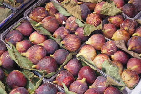 Fresh, succulent figs beautifully displayed alongside vibrant green leaves for decorationの写真素材